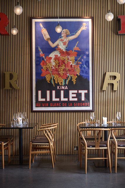 R Vinbars indretning med træpaneler, kunst og dækkede borde